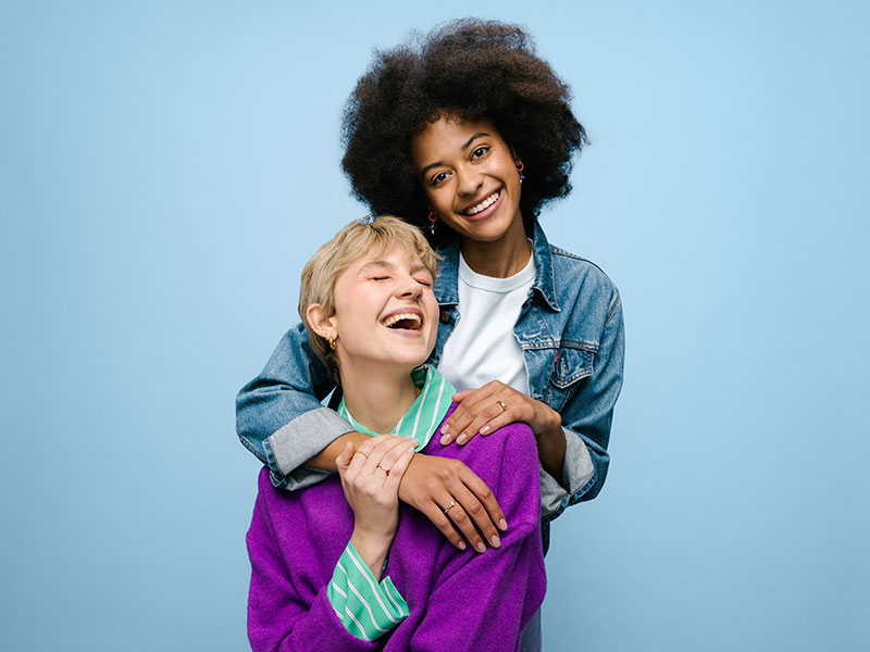 Zwei fröhliche junge Frauen, die sich umarmen und lachen