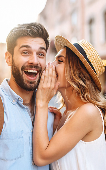 Frau flüstert Mann etwas ins Ohr