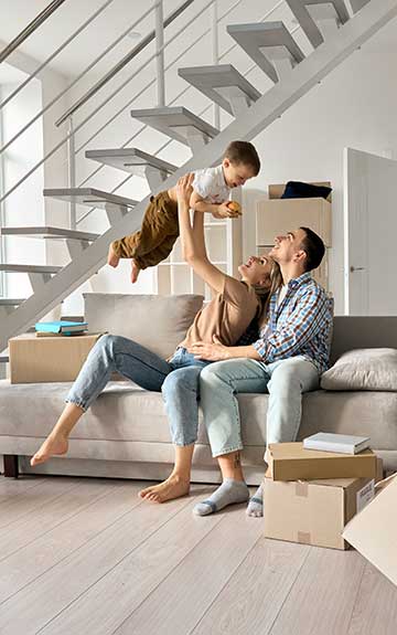Mutter und Tochter sitzen auf Sofa und sehen sich zusammen eine Bankomatkarte an