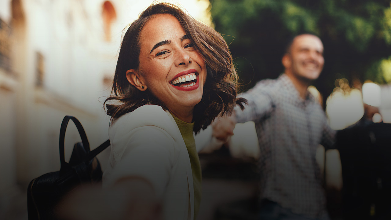 Eine Frau hält die Hand einer anderen Person, die man nicht sieht. Sie lächelt in die Kamera.