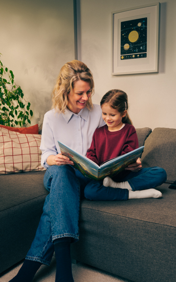 Mutter und Tochter sitzen auf Sofa und sehen sich zusammen eine Bankomatkarte an