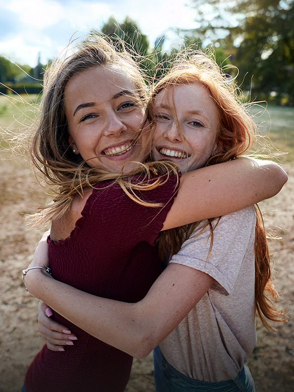 Zwei Frauen umarmen sich auf einer Wiese